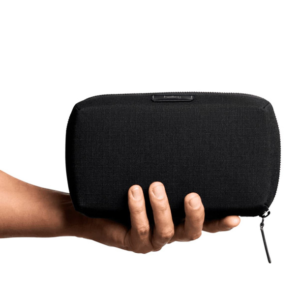 A black tech kit held in a hand, featuring a zip closure and a branding logo. A black tech kit held in a hand, featuring a zip closure and a branding logo.