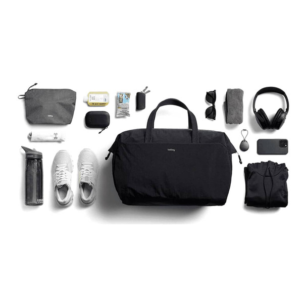 A black duffel bag surrounded by a water bottle, shoes, a hoodie, headphones, sunglasses, and various accessories.