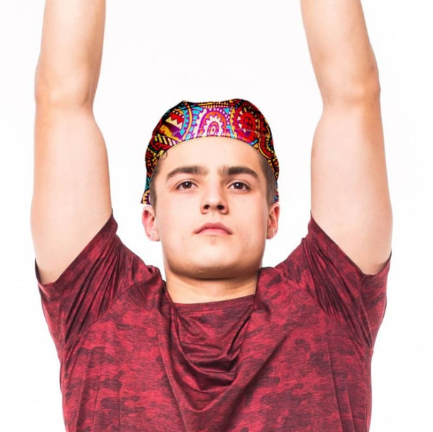 A person wearing a brightly patterned bandana, raising their arms, dressed in a red shirt. The bandana features vibrant colours.