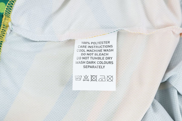 A care label on a 100% polyester micro mesh sports long sleeves shirt, featuring fabric care instructions.