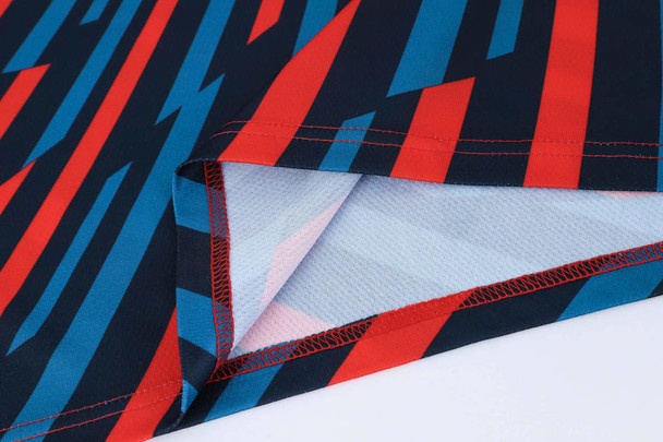 A close-up of a red, blue, and black patterned polyester polo shirt, featuring a logo and bold design elements.