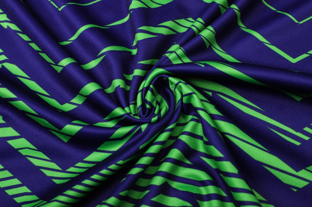 A vibrant navy and green patterned fabric, showcasing a wavy design with twisting folds.