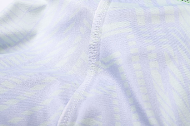 A close-up of a light-coloured, patterned fabric showcasing stitching details of a V-neck shirt.