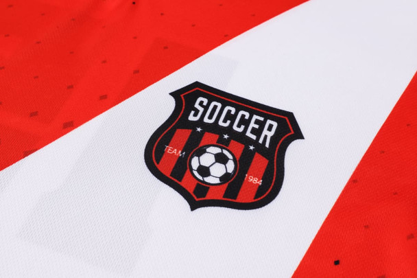 A red and white football jersey featuring a logo with a soccer ball and stripes.