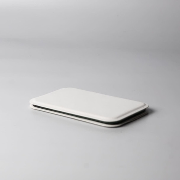 A pocket mirror in sleek white, featuring a minimalist design, resting on a light grey surface.