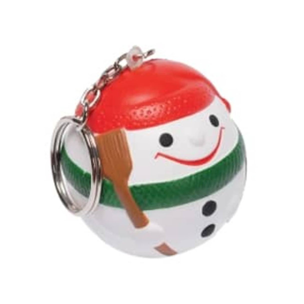A snowman-shaped stress ball keyring in white, red, and green with a smiling face and a wooden shovel.