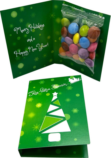 A green card featuring a Christmas tree design, containing a clear bag of colourful Smarties.