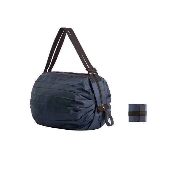 A foldable reusable shopping shoulder bag in navy blue, featuring a black strap and a compact folded design.