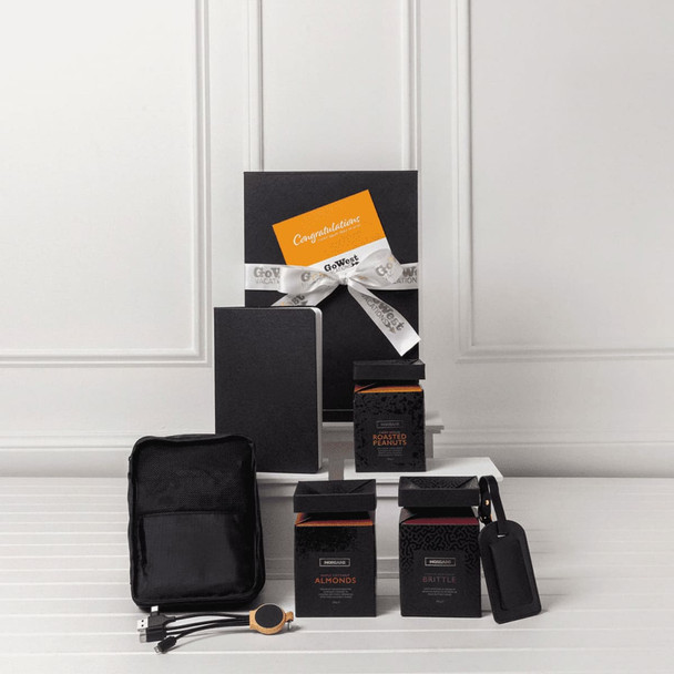 A travel kit featuring a notebook, two black boxes, a pouch, and a tag. All items are arranged on a white surface.