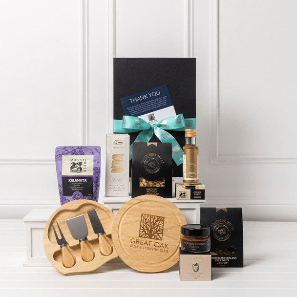 A gourmet entertainer set featuring wooden cheese tools, gourmet snacks, a bottle, and a gift box adorned with a ribbon.