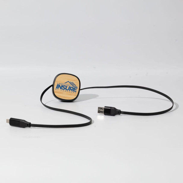 A black charging cable with a round, wooden connector end featuring a logo.