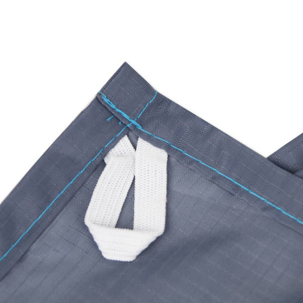 A close-up of a grey picnic blanket featuring a white handle and blue stitching, with a logo present.