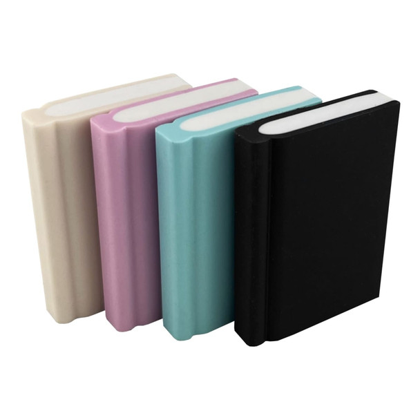Four book-shaped rubber erasers in cream, pink, teal, and black, featuring rounded edges and varying thicknesses.