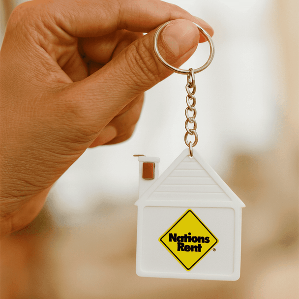A keyring featuring a house-shaped design in white, with a logo and a small chimney detail.