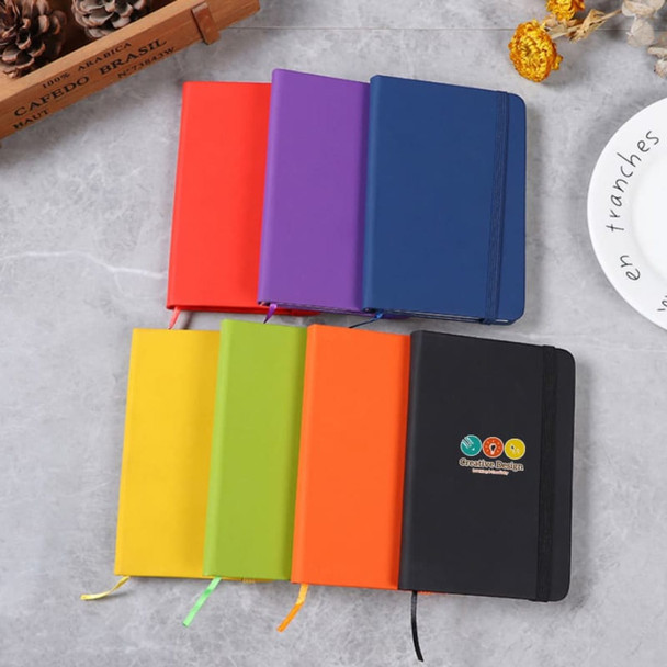 A collection of PU A6 notebooks in various colours: red, purple, green, orange, and black, with an emblem on one.