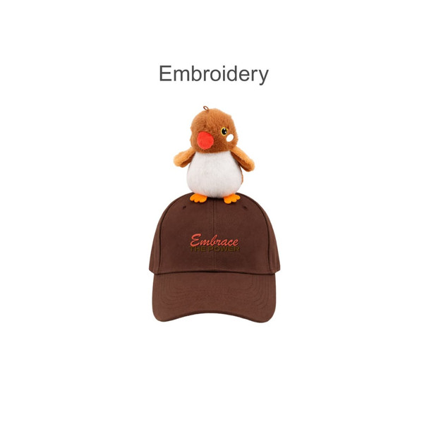 A brown baseball cap with a plush bird on top and decorated embroidery. The cap has a logo.