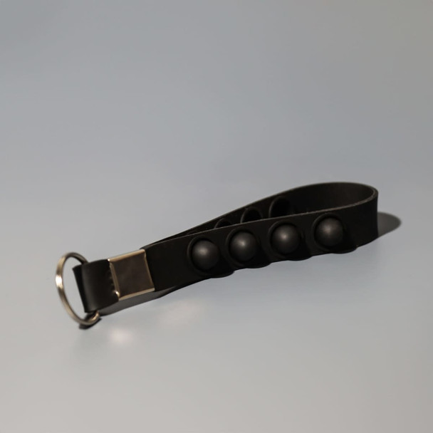 A black key chain stress reliever with popper buttons and a silver attachment ring.