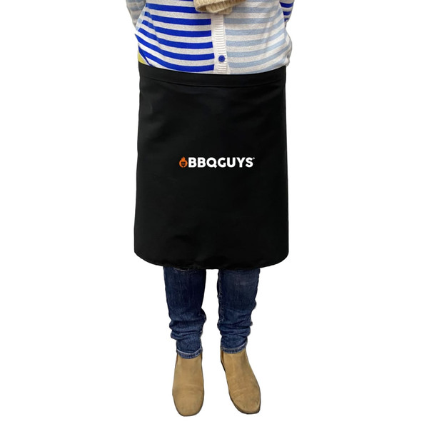 A black waist apron with a logo, worn by a person standing, dressed in casual attire.