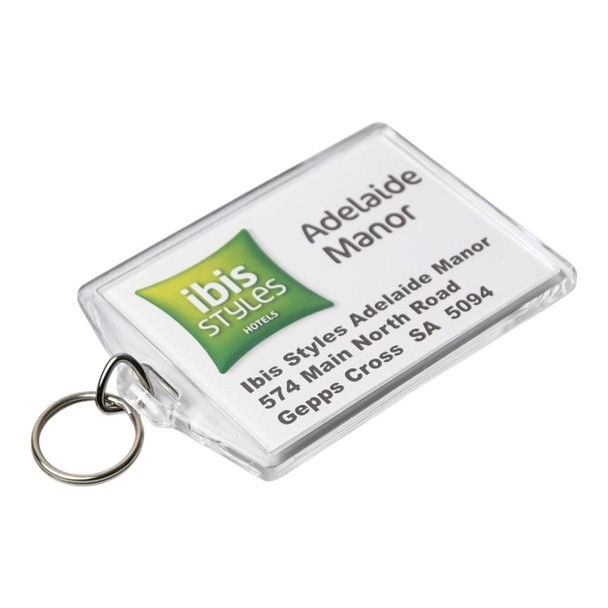 A clear hotel keychain featuring a logo and details for Ibis Styles Adelaide Manor, attached to a metal ring.