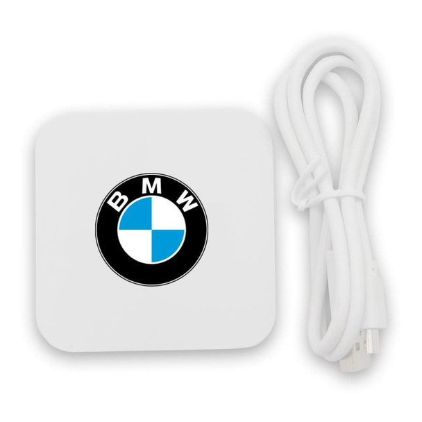 A wireless charging dock in white with a circular logo. Includes a USB cable.