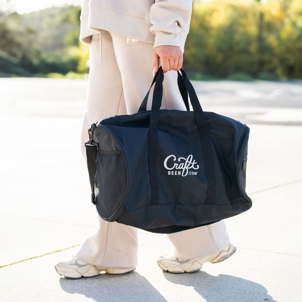 A person carrying a navy RPET duffle bag with handles and a shoulder strap. The bag features a logo.