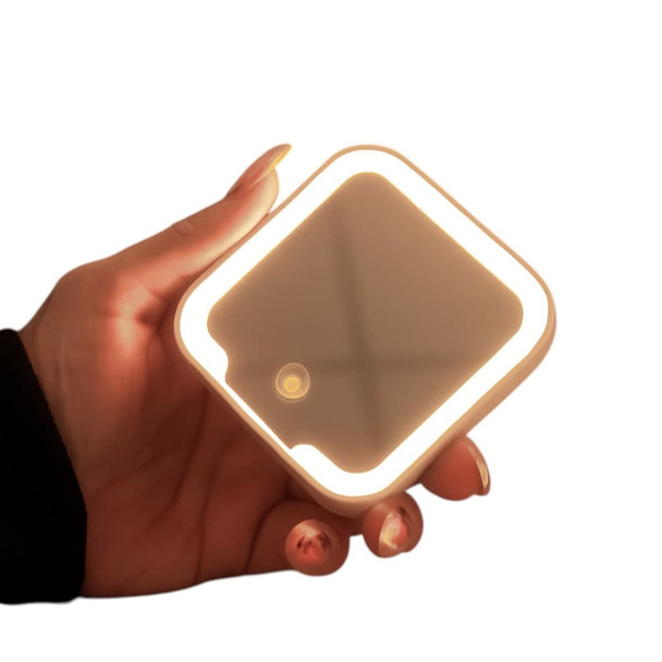 A compact square mirror with an LED light, held in a hand, featuring a soft glow and a neutral colour.