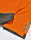 An orange polo shirt featuring grey accents and a logo on the hem.