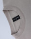 A crew neck sweater in a light beige colour, featuring a label and a soft fleecy texture.
