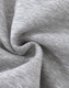 A close-up of soft, grey fabric with a slight texture, typical of a fleece jumper. It features a logo.