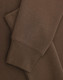 A brown crew fleece jumper with visible cuffs and fabric texture detail. Features a logo.