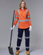 An orange work shirt with reflective stripes, paired with navy pants and work boots, held by a woman with a shovel.