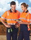 Two individuals wearing high-visibility orange and navy safety polo shirts with reflective stripes, standing outdoors.