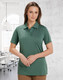 A green ladies' polo shirt featuring a collar and buttons, displayed in a bright office environment.