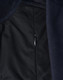 A close-up of a navy blue softshell jacket, featuring a zippered pocket and textured fabric.