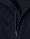A close-up of a navy softshell vest featuring a zippered front and a fleece lining. The vest has a logo on it.
