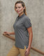 A grey women's poly/cotton polo shirt with short sleeves and a side split, displayed against a textured background.
