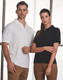 A black polo shirt on a woman and a white polo shirt on a man, both with a logo.