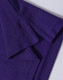 A close-up of a purple polo shirt, featuring a textured fabric and folded collar. The shirt has a logo.