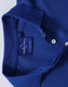 A close-up of a blue polo shirt, featuring a classic collar and buttons, with a label and a logo on the inside.