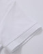 A white polo shirt featuring a textured fabric and a folded sleeve detail. It includes a logo.
