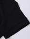 A close-up of a black polo shirt sleeve featuring a folded cuff and a subtle branding logo.