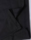 A close-up of black fabric showing the folded edge and stitching detail of a polo shirt. The fabric has a textured finish.