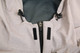 A close-up of a light grey waterproof performance jacket, featuring adjustable toggles and zip fastening.