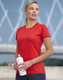 A woman wearing a red short-sleeved performance t-shirt holds a white drink bottle, set against a blurred outdoor background.