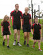 A group of four people wearing matching black and red Men's Alliance polo shirts and shorts, walking on grass.