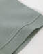A close-up of the hem of a men's cotton stretch polo in a soft green colour, featuring a knitted cuff.