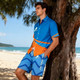 Knee-length men's swim shorts in blue with an abstract pattern, paired with a matching blue and orange shirt.