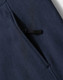 A close-up of a navy blue softshell hoodie featuring a zippered pocket. The fabric has a soft texture.