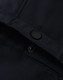 A close-up of a navy softshell jacket featuring a snap button and interior stitching details.