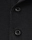 A close-up of a black polo shirt featuring two black buttons and a collar. It has a logo on the fabric.